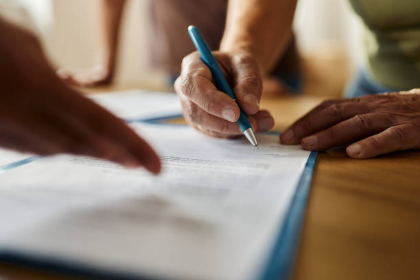Close up of unrecognizable person signing a contract in the office. signing papers